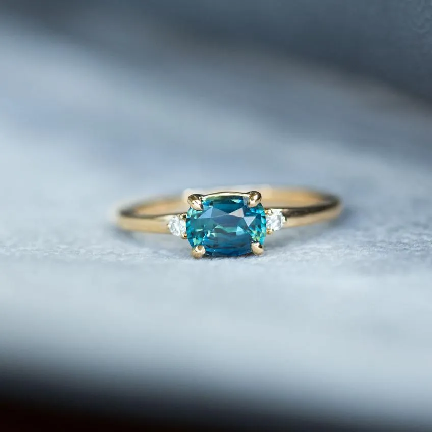 Teal Blue Three Stone Ring featuring 1.15ct cushion sapphire and diamonds in East-West setting